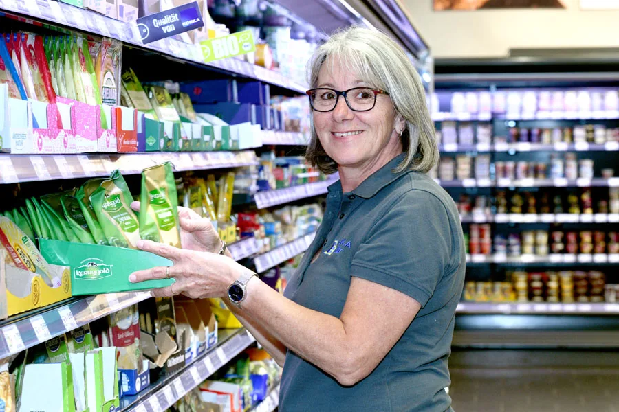 Mitarbeiterin von EDEKA Zeller räumt Ware in ein Kühlregal